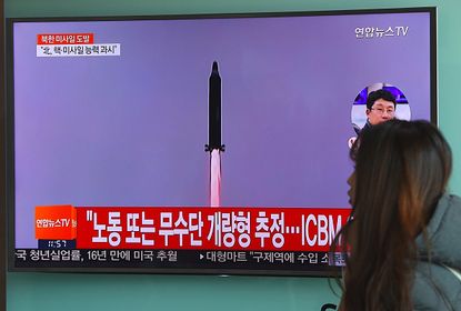 A woman walks past news footage of North Korea's missile launch.