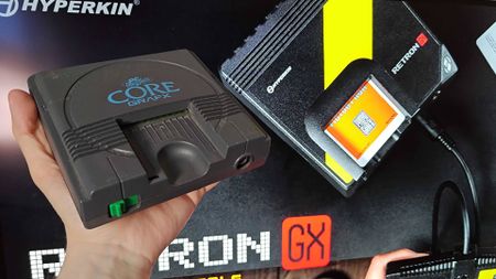 Hand holding PC Engine Core Grafx console in fromt of screen with new Hyperkin Retron GX displayed.