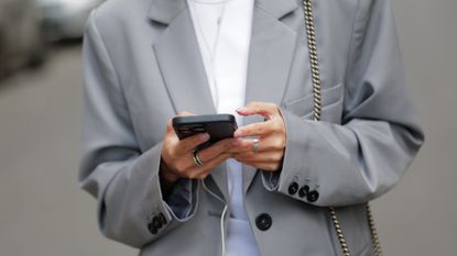 Diane Batoukina wears a white t-shirt, a pale gray blazer jacket, matching pale gray large suit pants, a black and gray FF monogram print pattern denim / velvet handbag from Fendi, during a street style fashion photo session, on April 07, 2023 in Paris, France. (Photo by Edward Berthelot/Getty Images)