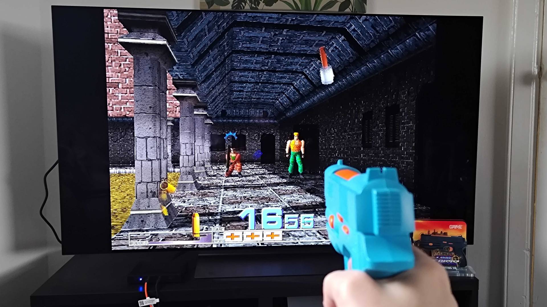 G&#039;AIM&#039;E Time Crisis Lightgun console running game with player holding gun towards screen.