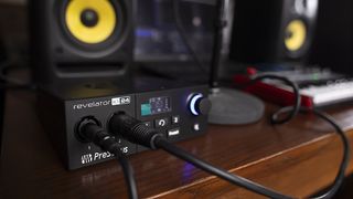 A PreSonus Revelator io24 on a desk with a MIDI keyboard and studio monitors