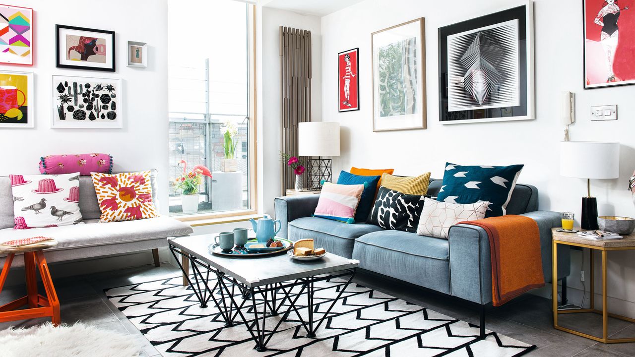 Light and dark grey sofas with variety of patterned cushions in colourful contemporary living room with industrial coffee table on black and white herringbone rug