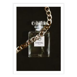 A black wall art print of a Chanel perfume bottle with a chain across it