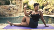 Woman doing seated yoga pose next to a pool