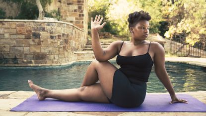 Woman doing seated yoga pose next to a pool