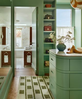 colors experts say to avoid in 2024, green walk in closet, with curved island, shelving, view of ensuite