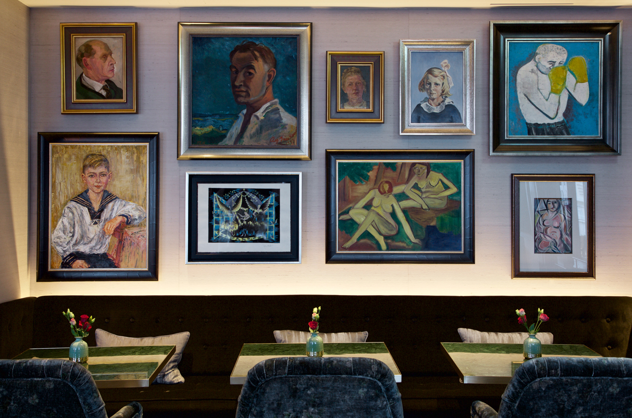 A gallery of paintings on a wall in a smart bar
