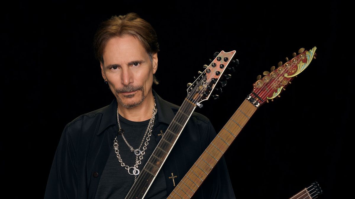 Steve Vai holding two guitars