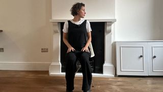 Naomi Annand performs head turns yoga move seated in a chair