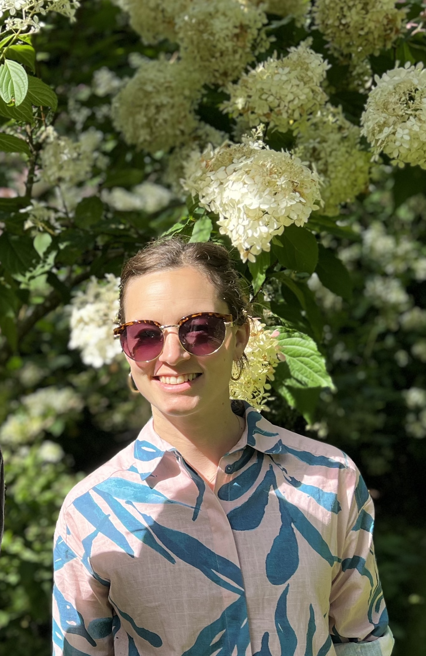 woman smiling to camera in front of trees