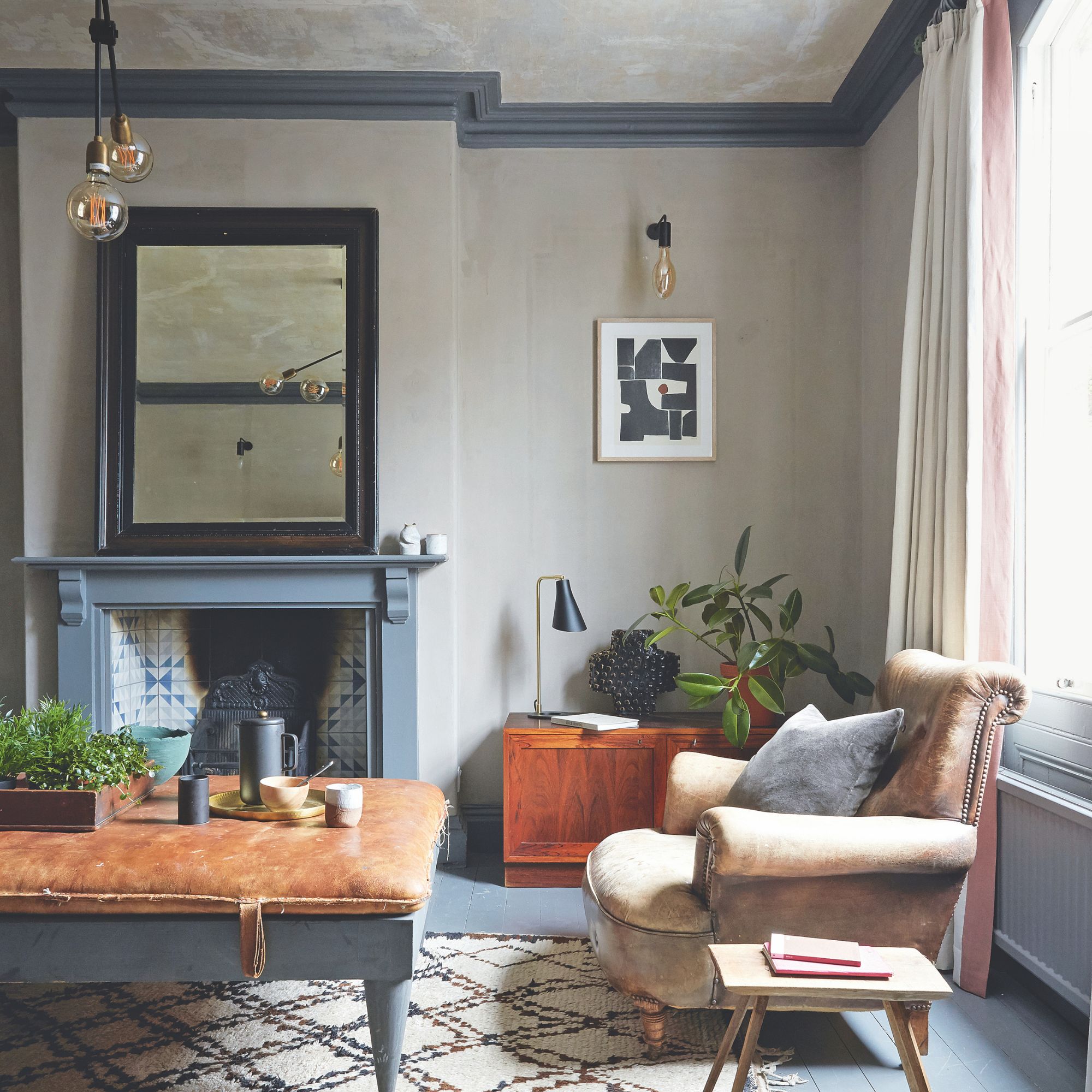 Living room with painted floorboards, fireplace and mirror and sofa