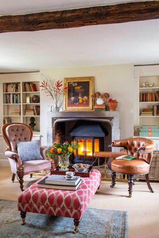 armchairs-either-side-of-a-burning-stove-with-footstool-in-beamed-living-room