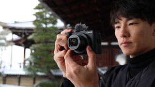 Canon PowerShot V1 in user's hands, oudoors with a snowy Japan backdrop