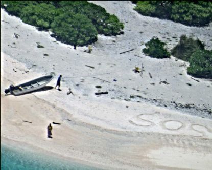 Two people were rescued from a desert island after they wrote 'SOS' in the sand