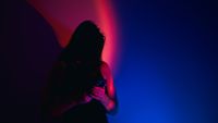 photo of a woman looking at a phone under stark red and blue light