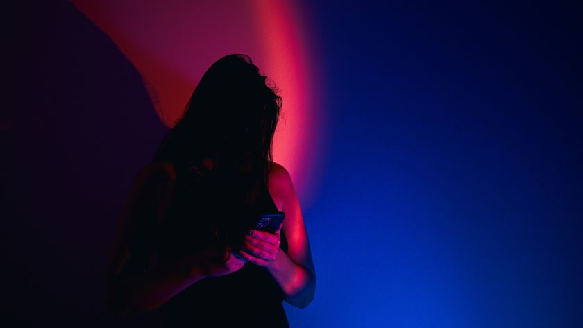 photo of a woman looking at a phone under stark red and blue light