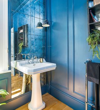 blue panelled bathroom with freestanding bath and mirrored splashback