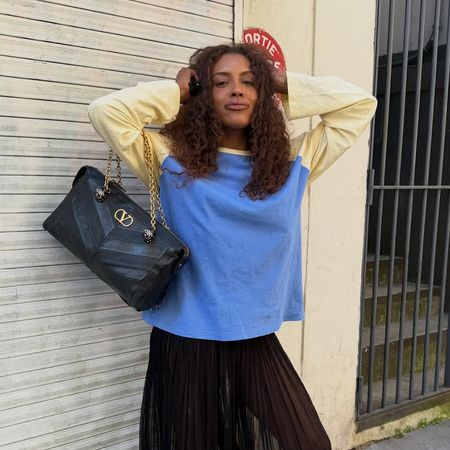 a woman wearing a yellow and blue longsleeve, sheer balloon pants, and red flats