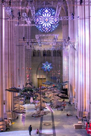 Two suspended phoenixes amidst the columns of the cathedral and with a blue, circular stained glass window beyond