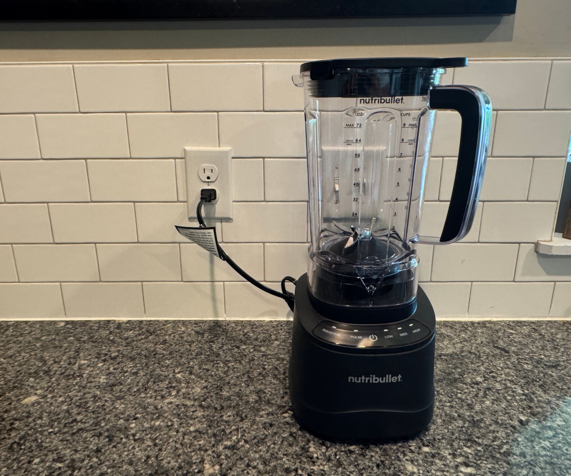 A nutribullet PowerCore XL Blender on a stone kitchen counter against white subway tiles.