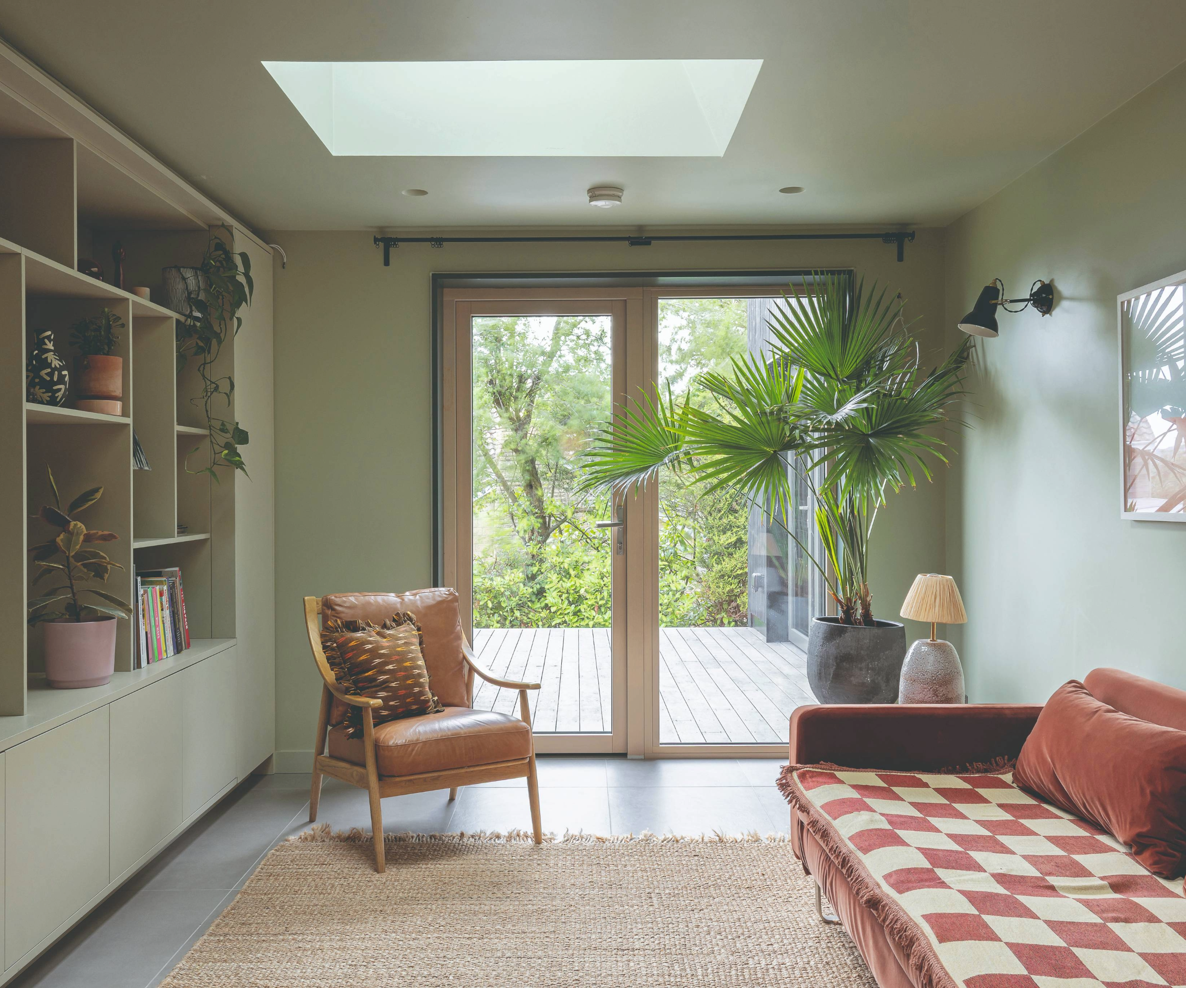 Inside the second living area with a pink sofa, big plant and build in shelving