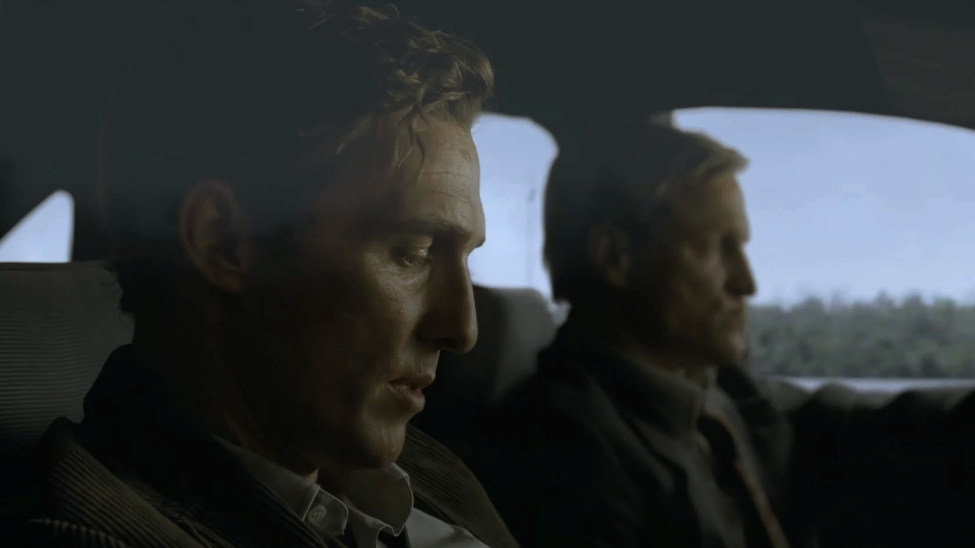 Matthew McConaughey and Woody Harrelson dressed in suits in a car in True Detective season 1.