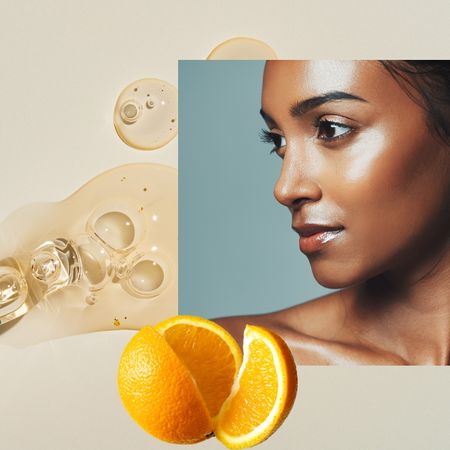 a woman with glowing skin on a tan background with a spill of clear serum and an orange