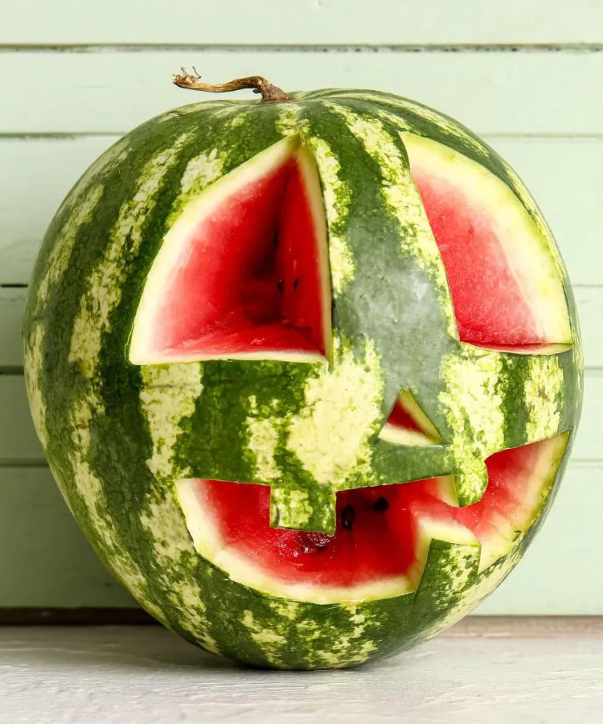 watermelon jack-o-lantern against a pale green wood background