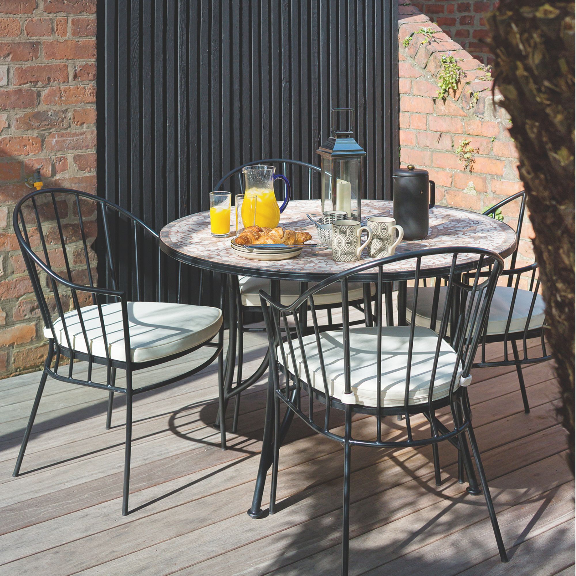Black bistro set on wooden decking in a small garden