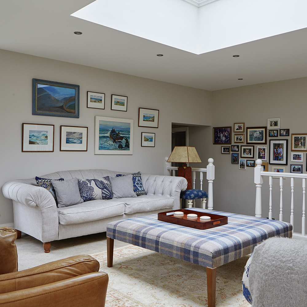 living area with white sofa with cushions and white wall with pictures
