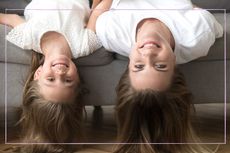 Mother and daughter laying with their heads over the side of the sofa