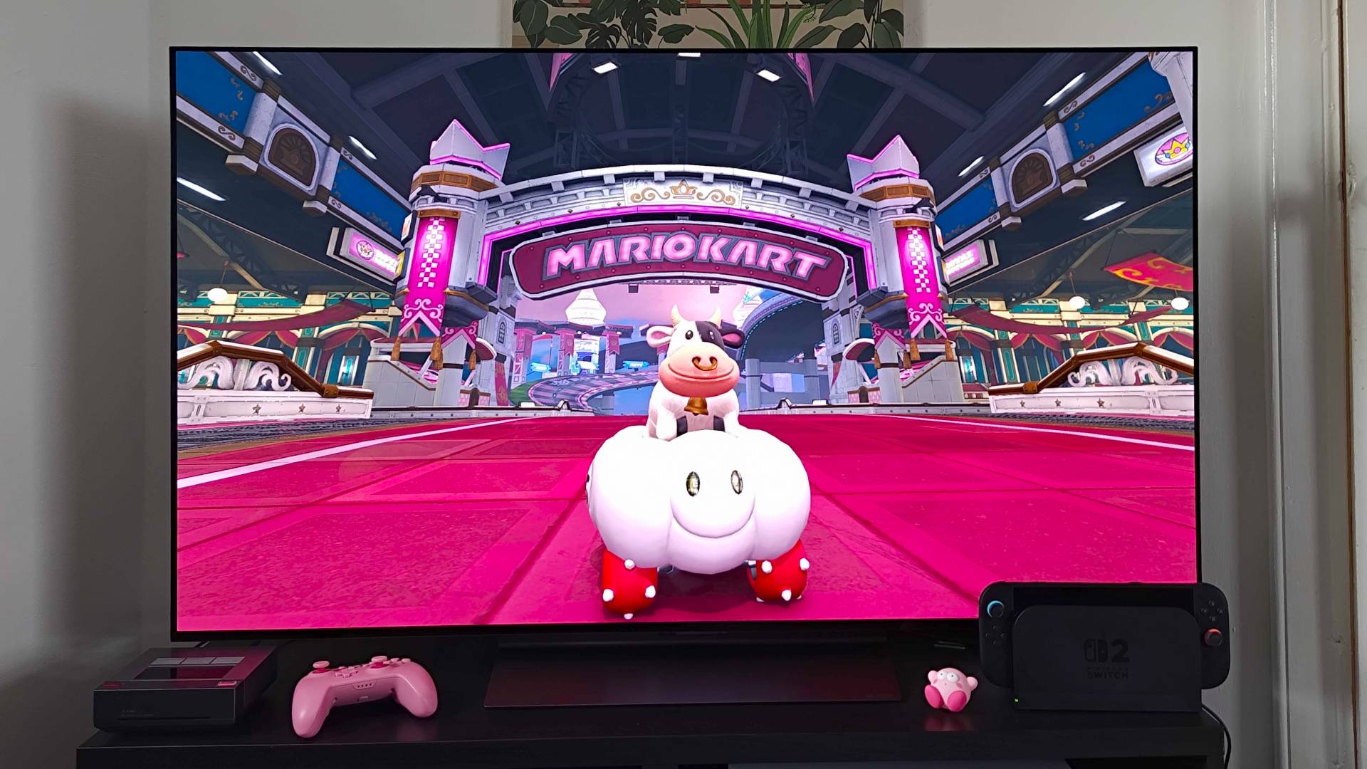 LG OLED C4 TV with Mario Kart World gameplay on screen featuring Cow in cloud cart at track start line.