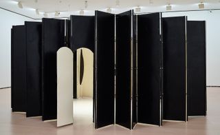 A wide black concertina screen with a white door in the centre.
