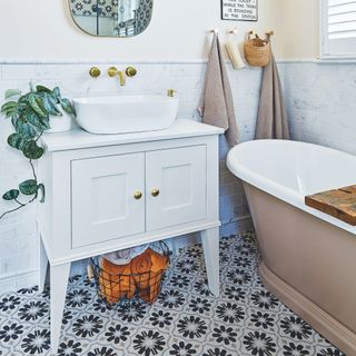 white bathroom with floral floor tiles and brown bath