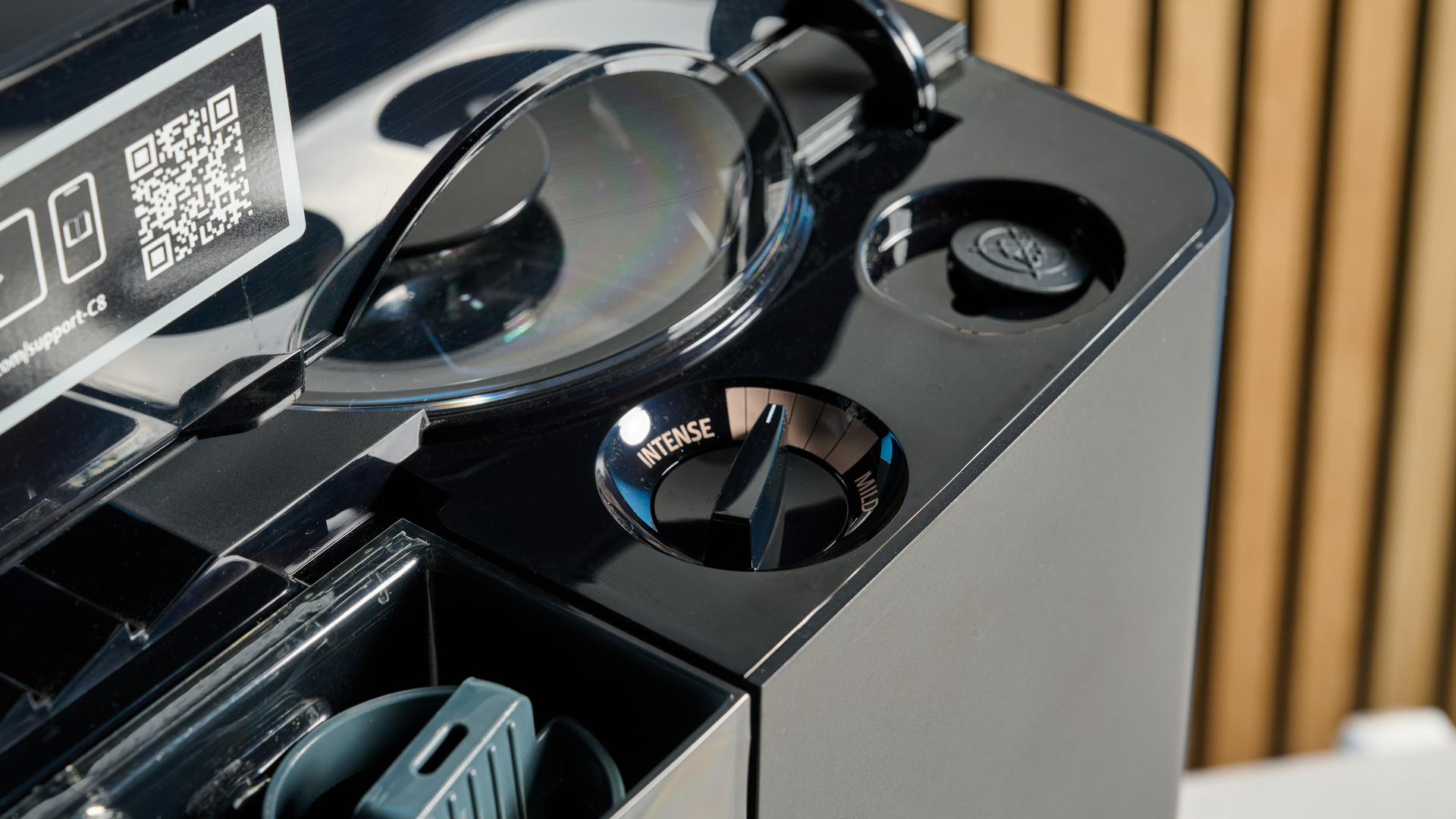 the jura c8 automatic coffee machine in piano black photographed with a blue and wood background