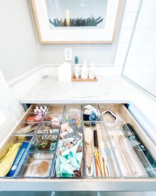 A bathroom drawer with organizers filled with items