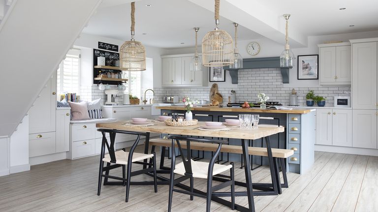 Kitchen-diner with blue Shaker-style island, black and wood dining table and chairs, rattan pendant lights and wooden floor