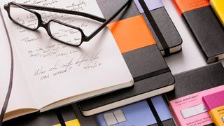 Moleskine notebooks with a pair of glasses resting on them