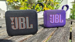 JBL Go 4 Bluetooth speakers on wooden table showing JBL logo