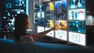 Beautiful Young Woman is Sitting on a Couch at Night at Home and Choosing a Movie to Watch on a Futuristic Augmented Reality Hologram Screen. Futuristic Concept. - stock photo