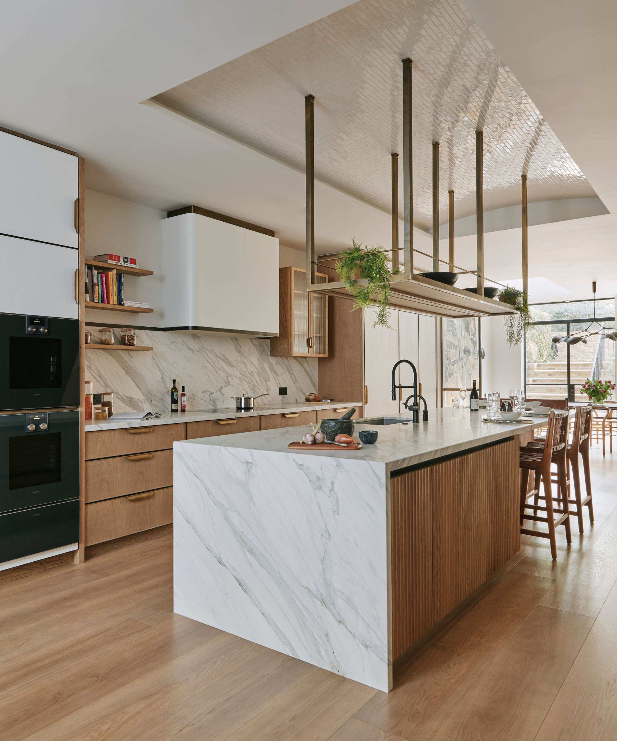 A warm wood kitchen that's light and bright with a waterfall marble island