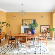 Dining area with mustard coloured walls and mid-century style furniture