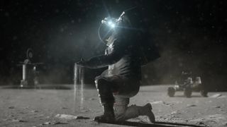 an astronaut in a bulky space suit kneels on a dusty grey surface, allowing dust to pour from their gloved hand