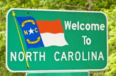 North Carolina state sign against bright green trees in the background