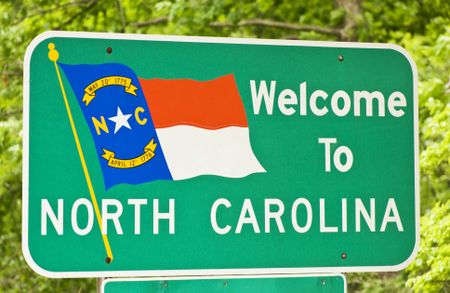 North Carolina state sign against bright green trees in the background