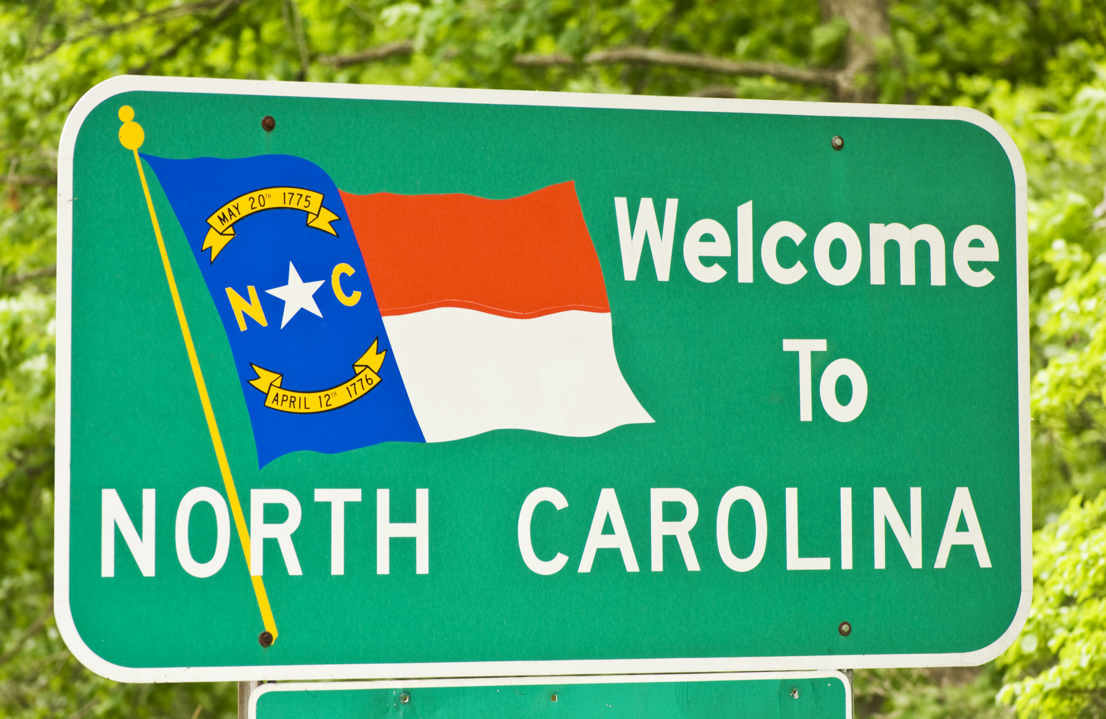 North Carolina state sign against bright green trees in the background