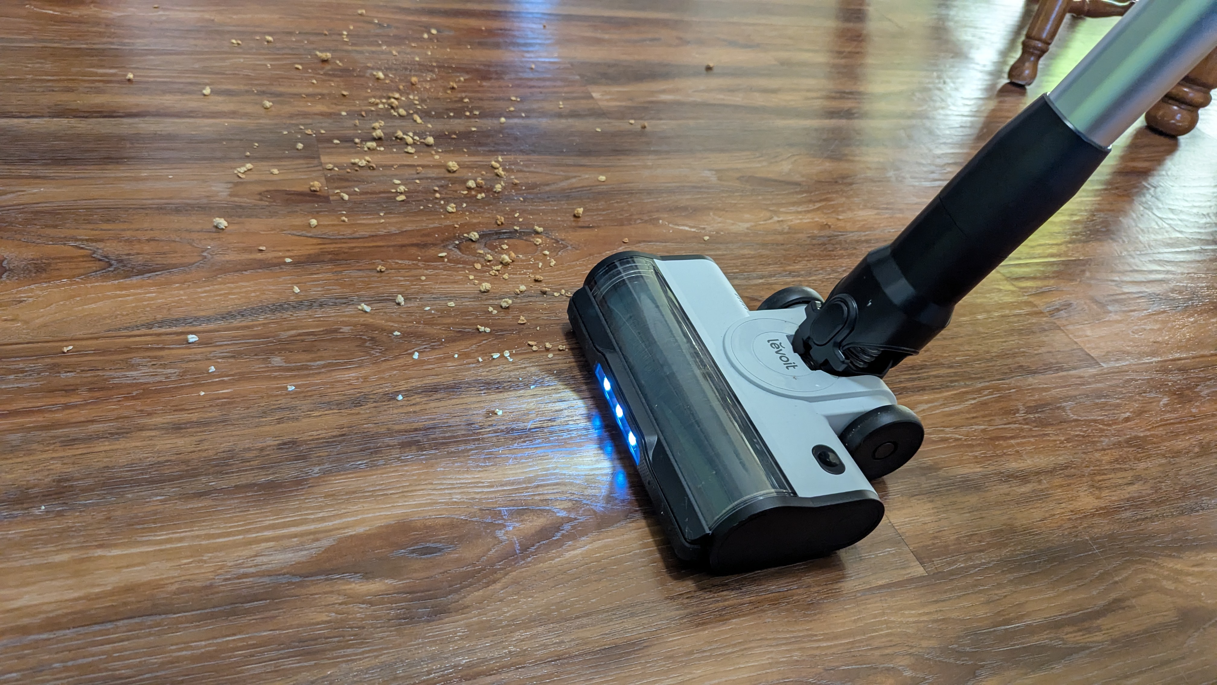 Levoit Aero vacuum being used to clear debris from a wooden floor