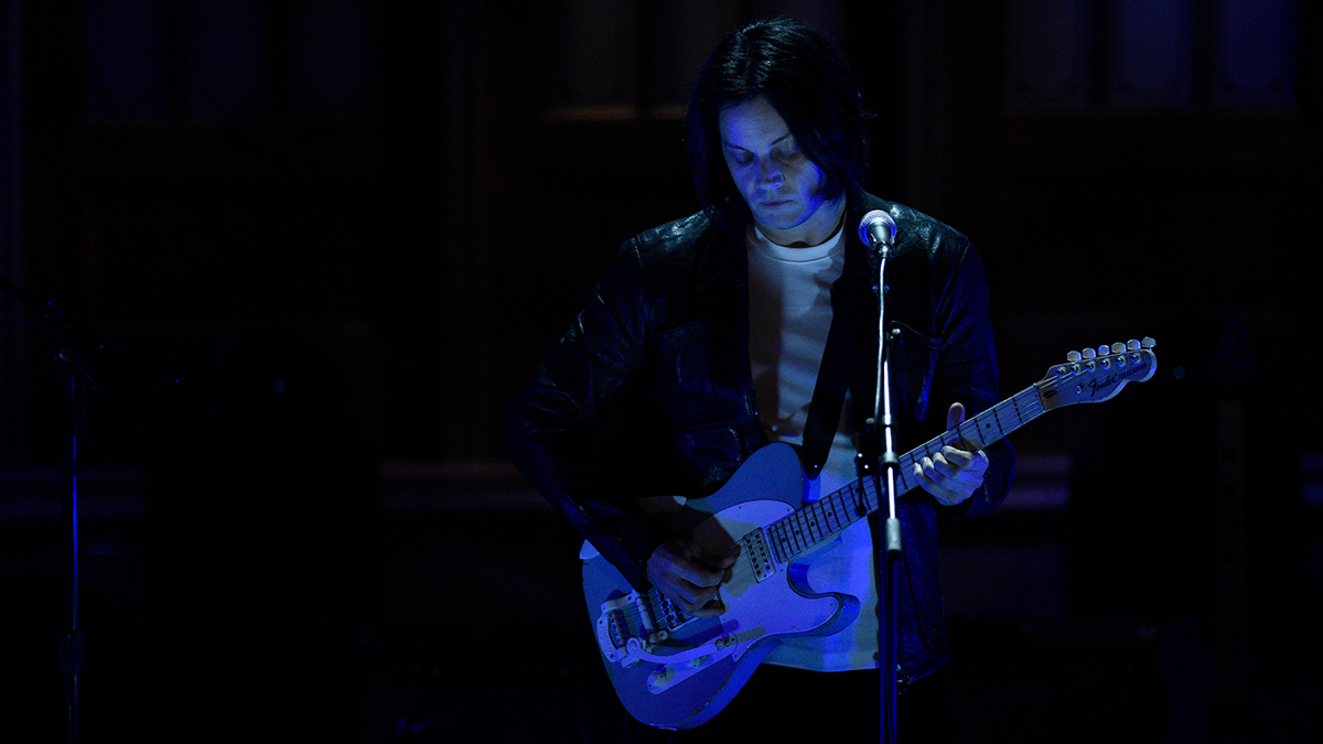 Jack White playing guitar with a dark background