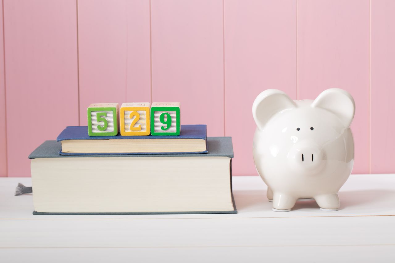 Saving for the costs of education with 529 plan concept with piggy bank standing alongside stacked textbooks.