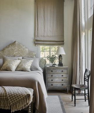 A powder grey bedroom with taupe curtains and soft furnishings